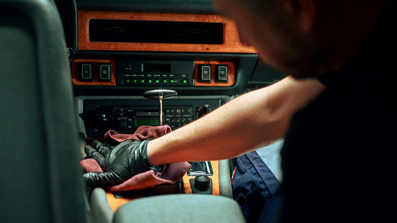 A detailer cleaning a wood-trim center console during an interior detail