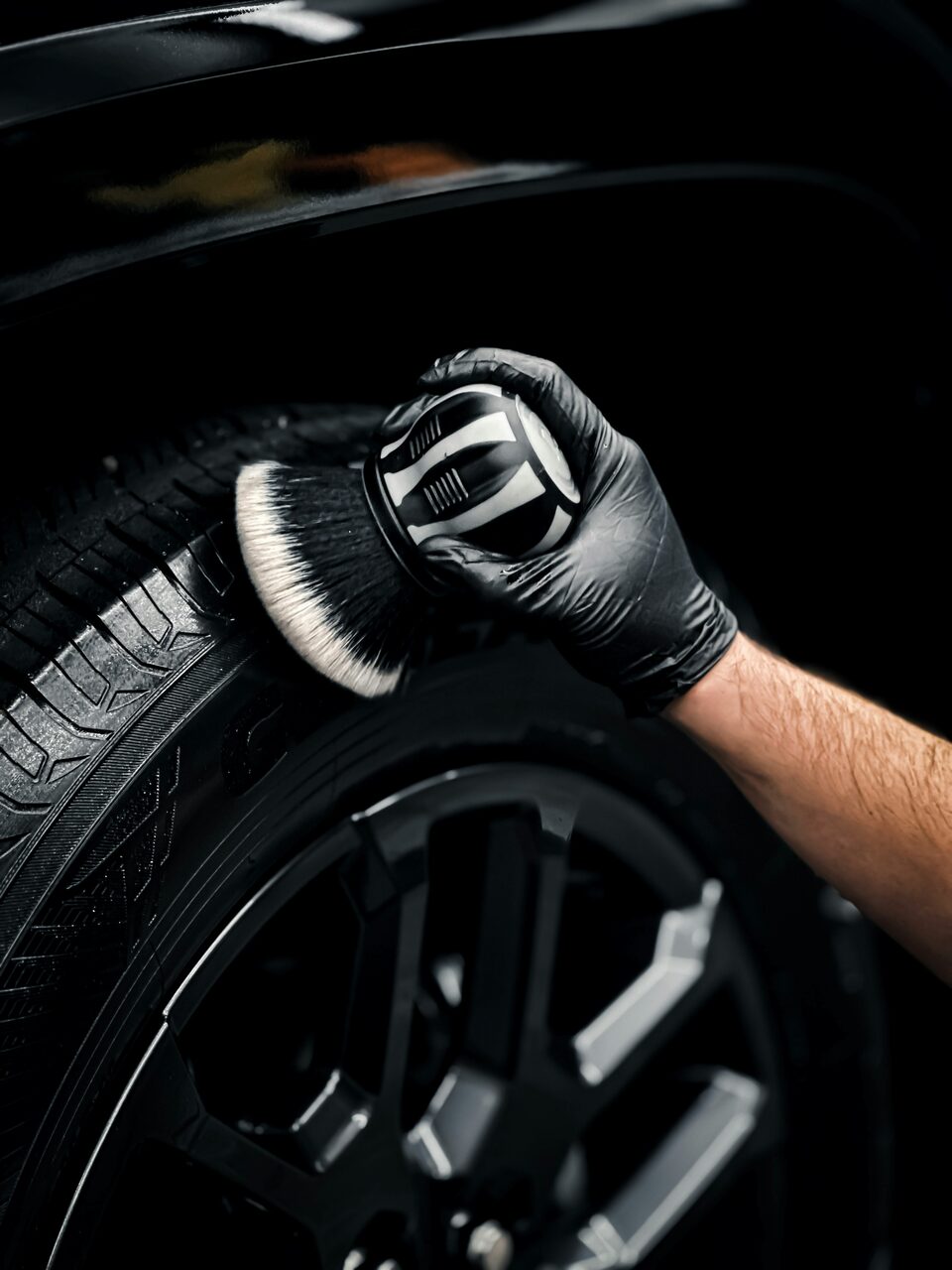 Applying tire dressing with a detailing brush on a black wheel